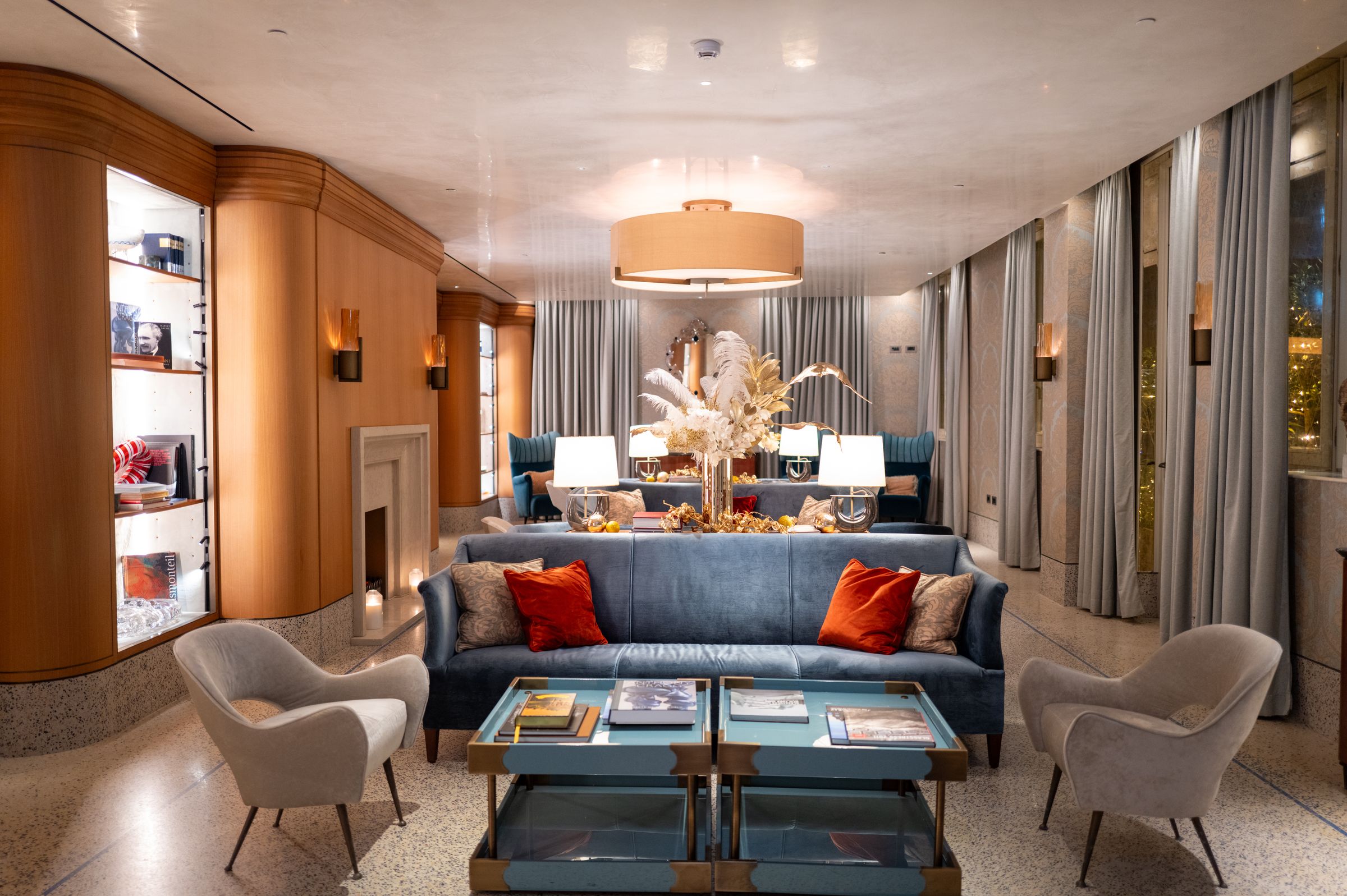 A warmly lit living room with layered seating, books, and colorful accents