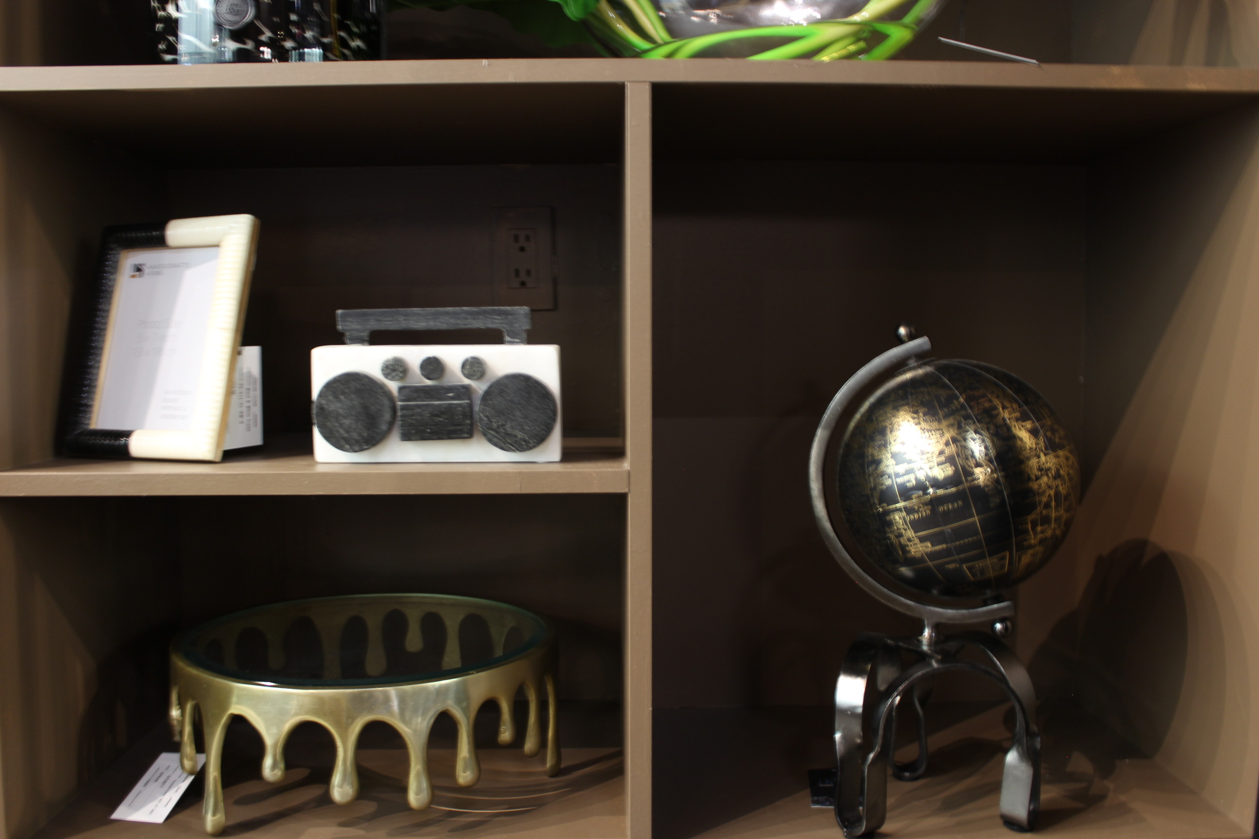 A dark showroom shelf styled with a sculptural globe and decorative objects