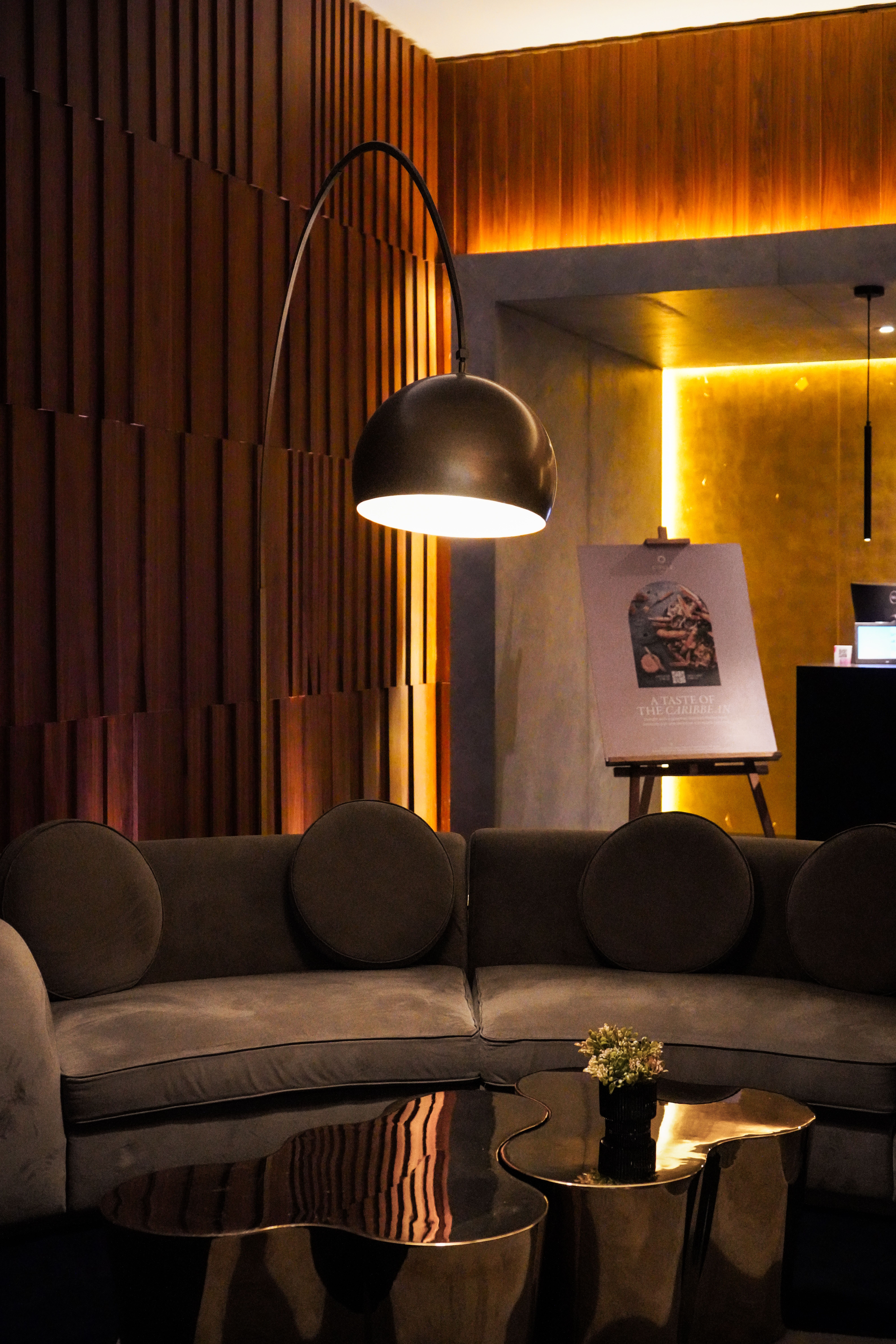 A warmly lit lounge with curved seating and sculptural tables