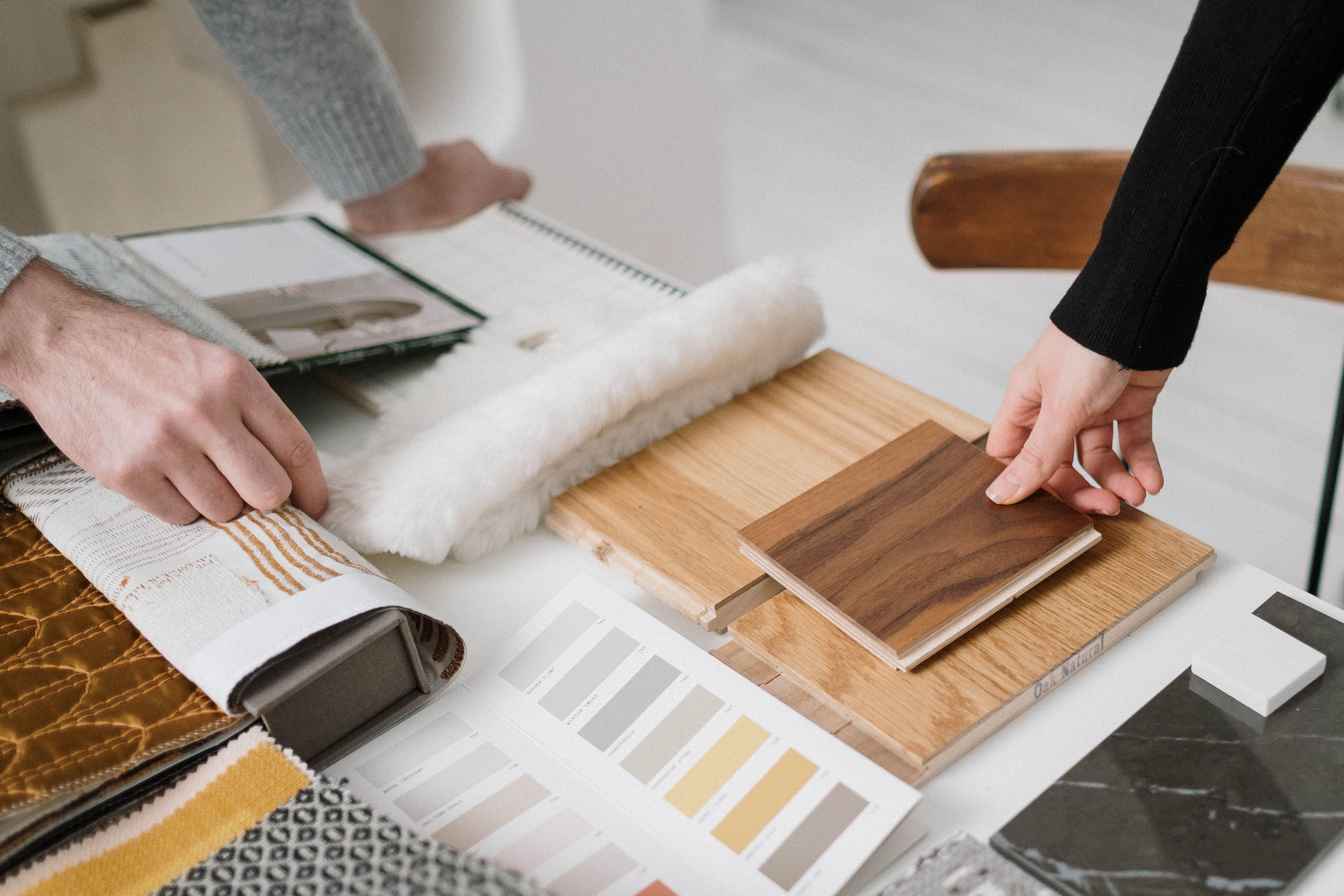 Hands comparing wood finishes, textiles, and paint colors